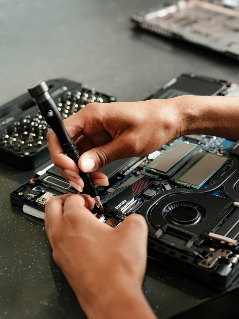 Hands repairing an open laptop